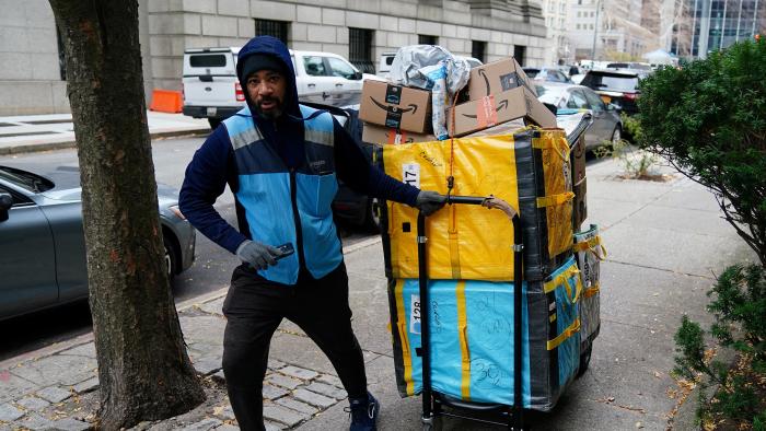 FILE PHOTO: An Amazon delivery person pulls a cart full of packages in the Manhattan borough of New York City, New York, U.S., December 10, 2021.  REUTERS/Carlo Allegri/File Photo