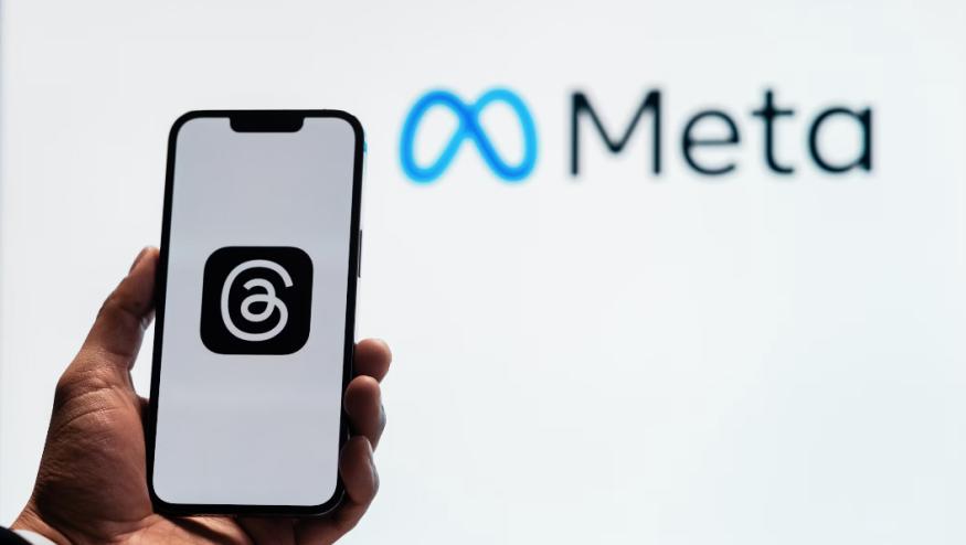 Logo on a phone with Meta sign in background.