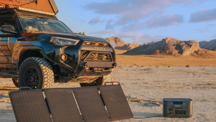 An SUV parked in a remote desert-like area has the BioLite BaseCharge 1500 and SolarPanel rigged to collect a charge from the sun.