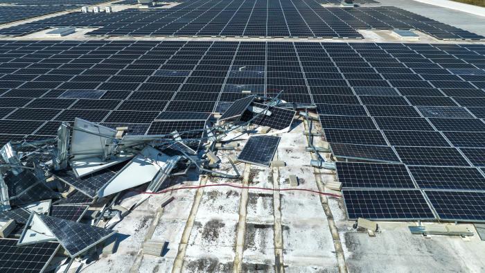 Broken down photovoltaic solar panels destroyed by hurricane Ian winds mounted on industrial building roof for producing green ecological electricity. Consequences of natural disaster.